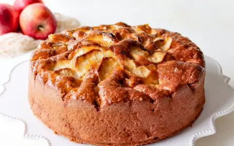 Bizcocho de manzana esponjoso, dorado y brillante, con trozos de manzana caramelizada en la superficie. ¡Perfecto para tu próxima receta!