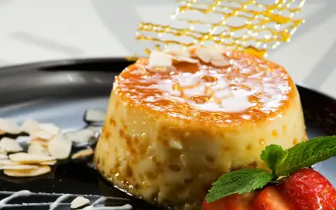 Delicioso postre de piña y leche condensada, cubierto de caramelo y decorado con almendras y fresas.
