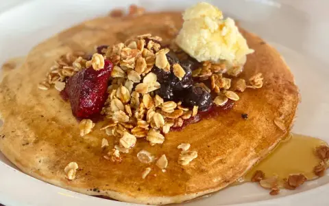 Deliciosos crepes con harina de almendras, cubiertos con granola, frutos rojos, arándanos y una porción de mantequilla.