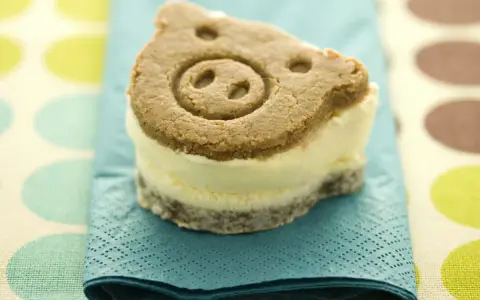 Un delicioso helado de galleta con forma de cerdito, servido sobre una servilleta azul turquesa.