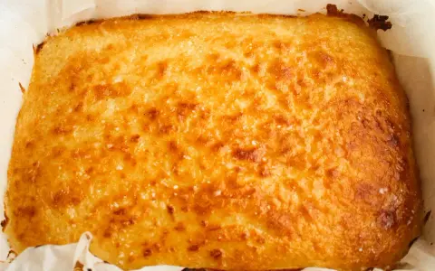 Un delicioso blondie dessert recién horneado, dorado y crujiente, listo para ser cortado y disfrutado.