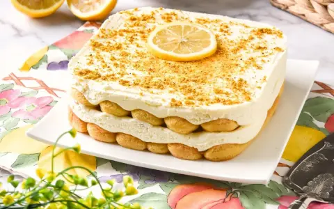 Delicioso tiramisú de limón, con capas de bizcochos y crema, coronado con una rodaja de limón y ralladura dorada.