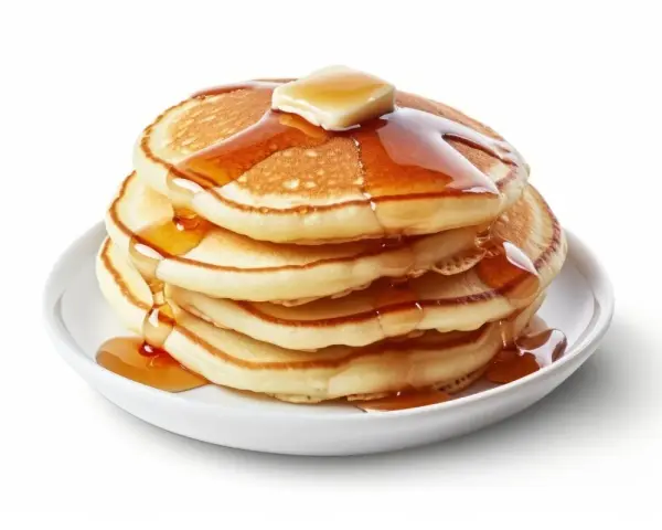 Pila de pancakes dorados con mantequilla y sirope cayendo. ¡Perfectos para tu receta de pancakes!