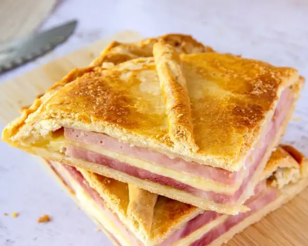 Dos porciones de empanadillas de jamón y queso, con capas doradas de masa y relleno generoso, listas para disfrutar.
