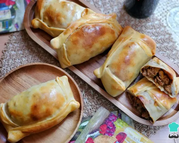 Deliciosas empanadas chilenas doradas, una rellena de carne cortada para mostrar su jugoso interior.