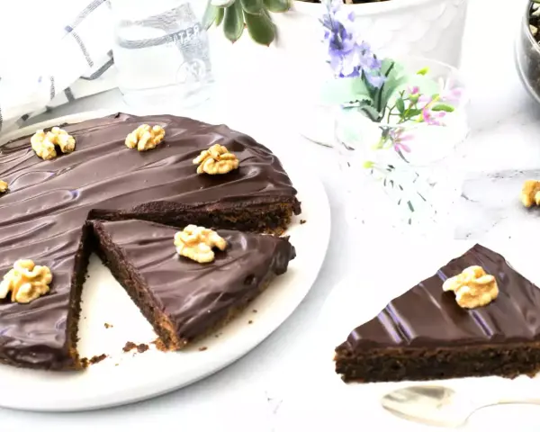 Delicioso pastel alemán de chocolate cubierto con glaseado brillante y nueces. Una rebanada ya servida.