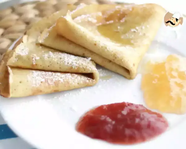 Deliciosos crepes sin gluten, espolvoreados con azúcar glas y acompañados de mermelada de fresa y melocotón.
