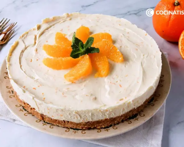 Tarta de naranja cremosa, decorada con gajos de naranja y menta. Perfecta para disfrutar de un postre refrescante.