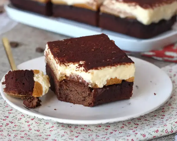 Un trozo de brownie de chocolate con una capa cremosa y espolvoreado de cacao. ¡Un delicioso brownie chocolate blanco!