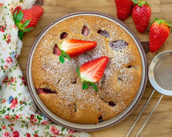Delicioso bizcocho de fresa, espolvoreado con azúcar glas y decorado con fresas frescas. Un postre casero perfecto.