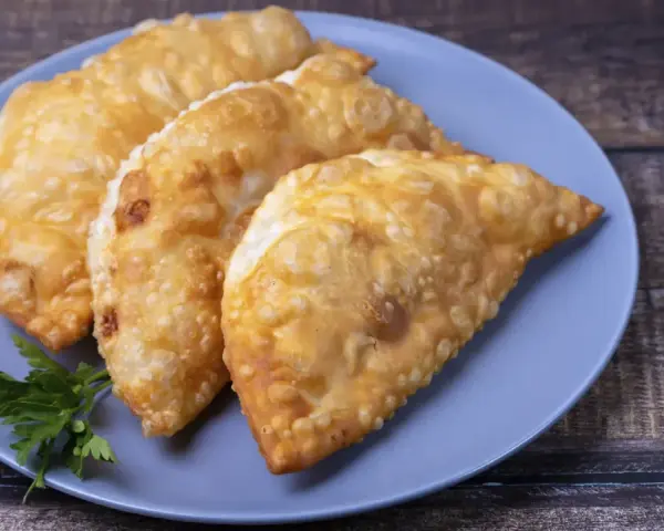 Tres empanadas doradas y crujientes, perfectas para tus recetas con obleas de empanadillas. Decoradas con perejil fresco.