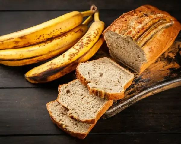 Plátanos maduros junto a un delicioso banana bread recién horneado, con rebanadas listas para disfrutar.