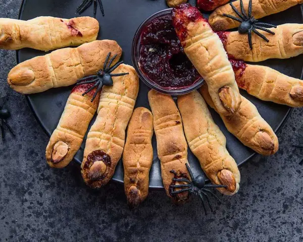 Galletas con forma de dedos, decoradas con almendras como uñas y mermelada roja simulando sangre. Un espeluznante postre de Halloween.
