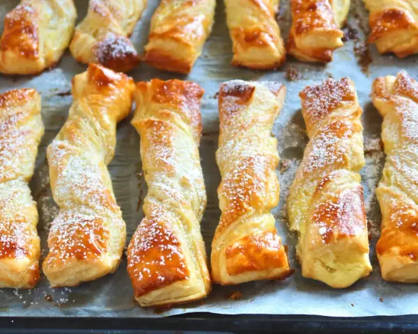 Deliciosos lazos de hojaldre dorados y espolvoreados con azúcar glas, listos para disfrutar.