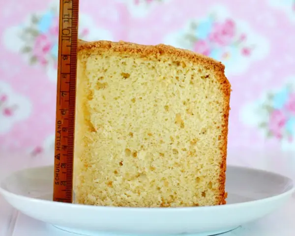 Rebanada de bizcocho de yogurt esponjoso, con una regla de madera al lado para medir su altura.