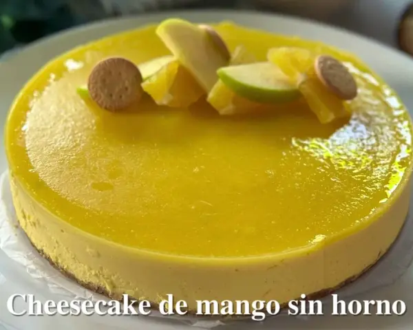 Tarta de queso y mango sin horno, decorada con trozos de manzana, naranja y galletas. ¡Un postre refrescante y delicioso!