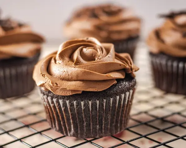 Deliciosas magdalenas sin huevo con glaseado de chocolate cremoso, decoradas como una rosa.