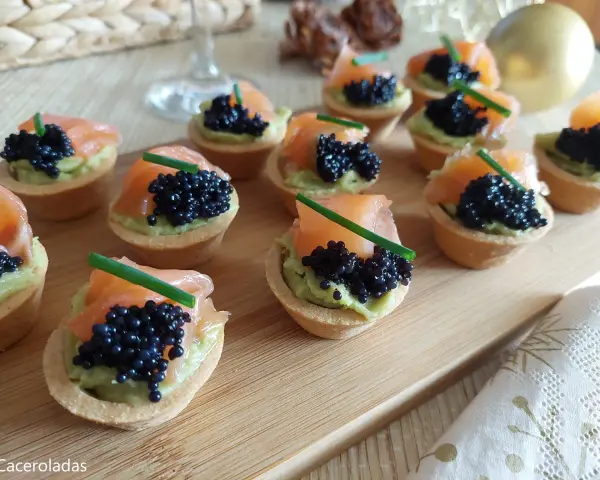 Deliciosas tartaletas de salmón y aguacate, coronadas con caviar negro y cebollino. Un bocado elegante y sabroso.