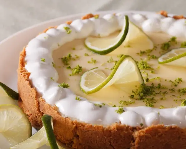 Delicioso key lime pie con merengue, rodajas de lima y ralladura verde.