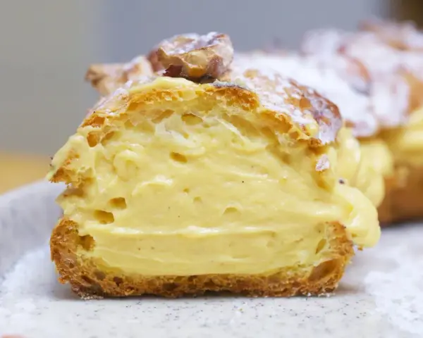 Un delicioso paris brest, un postre francés con crema pastelera y almendras, espolvoreado con azúcar glas.