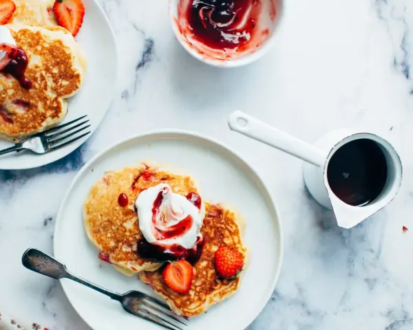 Deliciosas tortitas con fresas y nata, listas para servir. Aprende como hacer tortitas perfectas para el desayuno.