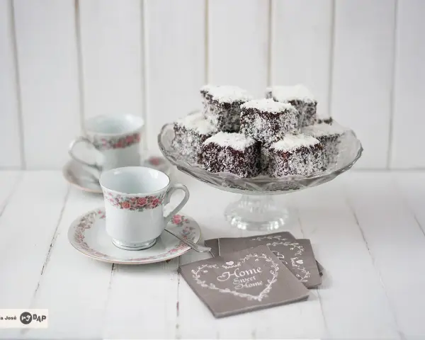 Deliciosos lamington cake cubiertos de coco, listos para disfrutar con café.