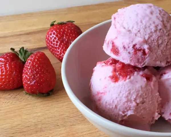 Delicioso helado de frutos rojos con fresas frescas al lado, listo para disfrutar en un día caluroso.