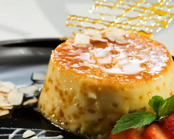 Delicioso postre de piña y leche condensada, cubierto de caramelo y decorado con almendras y fresas.