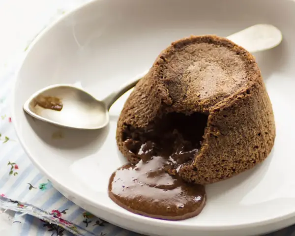 Coulant de chocolate recién horneado, con su interior líquido de chocolate derretido, listo para ser disfrutado con una cuchara.