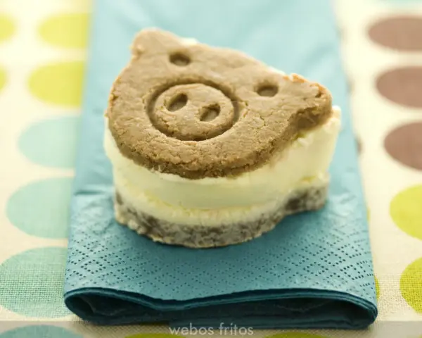 Un delicioso helado de galleta con forma de cerdito, servido sobre una servilleta azul turquesa.