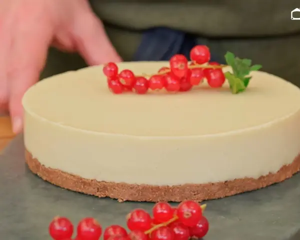 Deliciosa tarta de chocolate blanco, decorada con grosellas rojas y una hoja de menta.