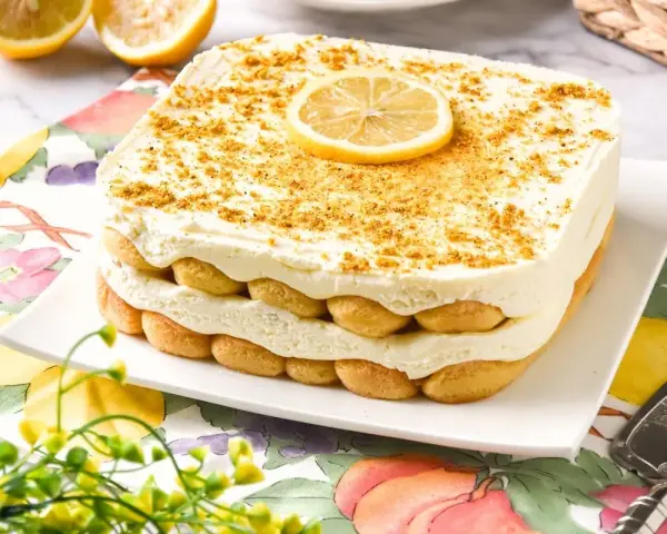 Delicioso tiramisú de limón, con capas de bizcochos y crema, coronado con una rodaja de limón y ralladura dorada.