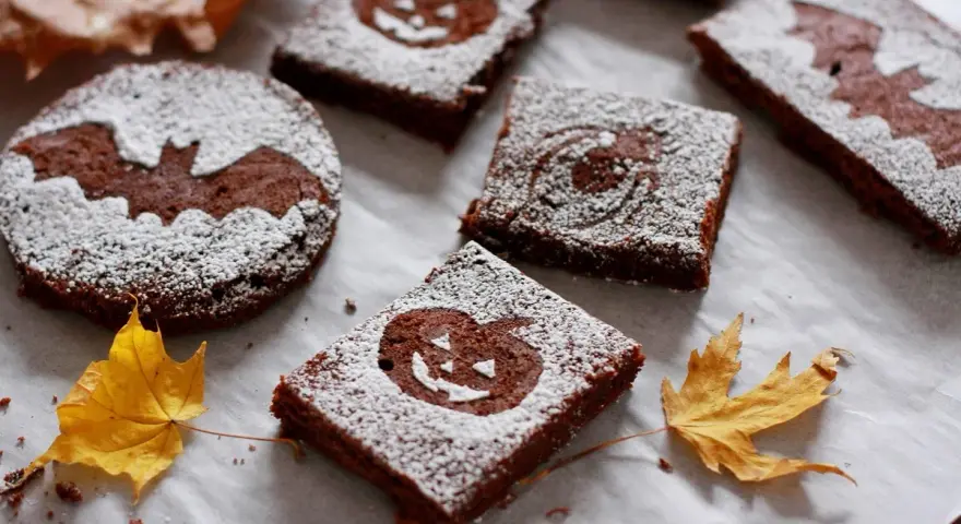 Deliciosos brownie halloween con calabazas y murciélagos, espolvoreados con azúcar glas.