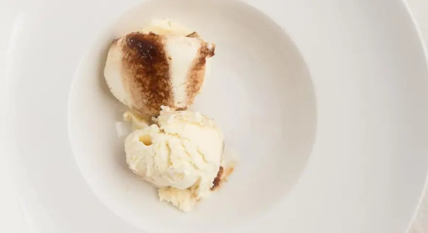 Dos bolas de helado de tiramisú con un toque de cacao en polvo en un cuenco blanco.