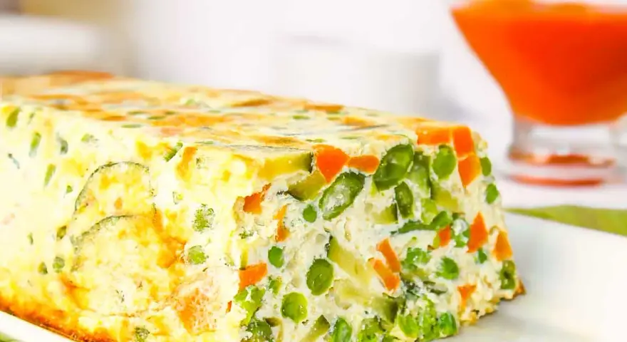 Pastel de verduras casero, con guisantes, zanahoria y calabacín, servido en un plato blanco.