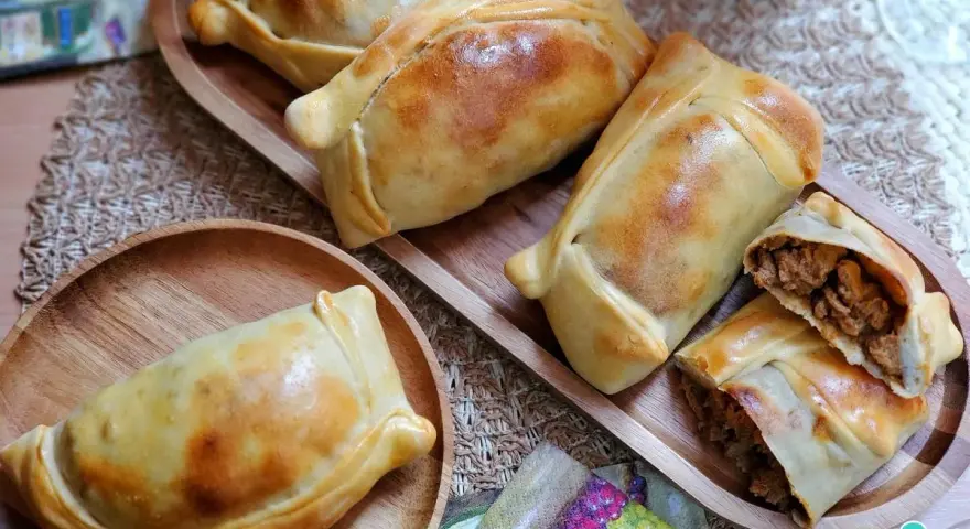Deliciosas empanadas chilenas doradas, una rellena de carne cortada para mostrar su jugoso interior.