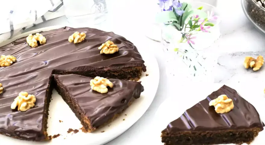 Delicioso pastel alemán de chocolate cubierto con glaseado brillante y nueces. Una rebanada ya servida.