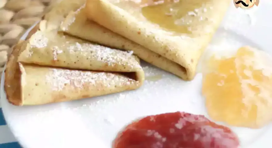 Deliciosos crepes sin gluten, espolvoreados con azúcar glas y acompañados de mermelada de fresa y melocotón.