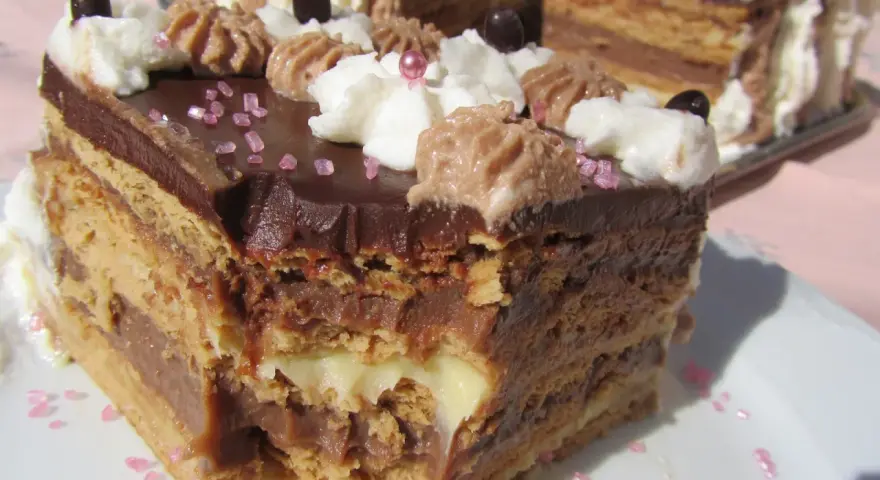 Delicioso postre Thermomix en capas de bizcocho y crema de chocolate, decorado con nata y granillo rosa.