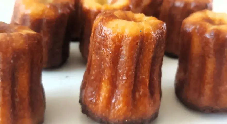 Un grupo de canelés de Bordeaux, con su característica corteza dorada y acanalada, listos para ser disfrutados.