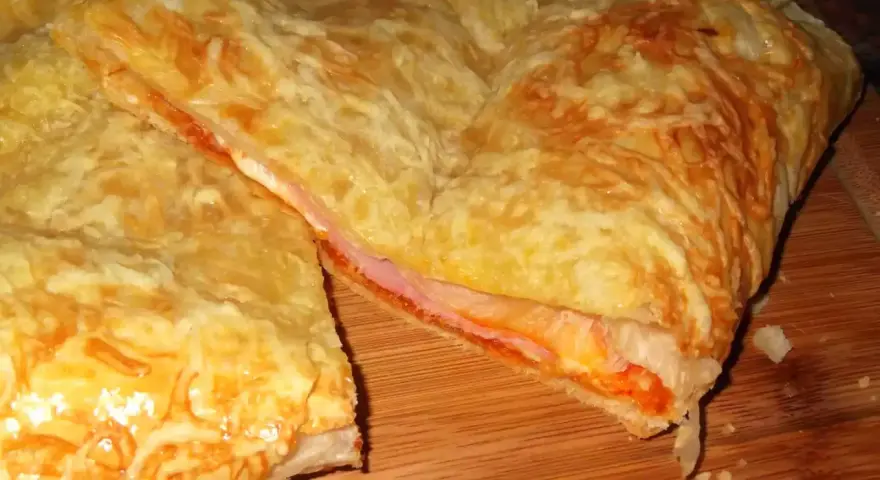 Empanada de jamón y queso dorada, con queso gratinado y relleno jugoso. ¡Un bocado delicioso!