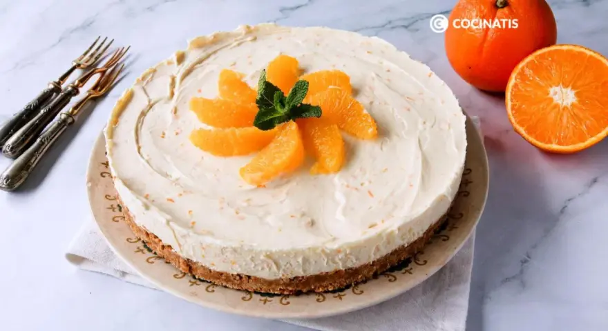 Tarta de naranja cremosa, decorada con gajos de naranja y menta. Perfecta para disfrutar de un postre refrescante.