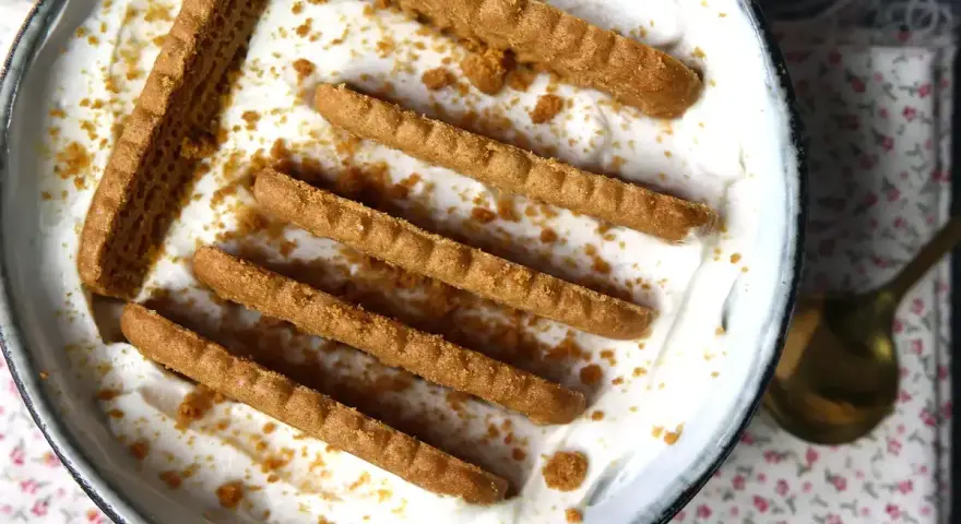Delicioso postre con yogur natural sin horno, decorado con galletas crujientes y migas.