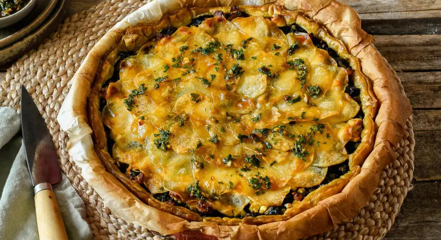 Delicioso quiche de espinacas con patatas laminadas y hierbas frescas, listo para servir.