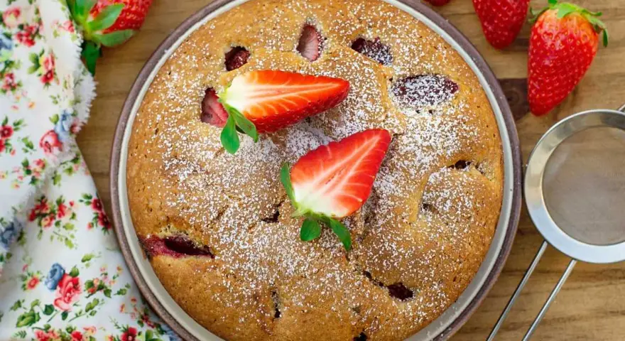 Delicioso bizcocho de fresa, espolvoreado con azúcar glas y decorado con fresas frescas. Un postre casero perfecto.