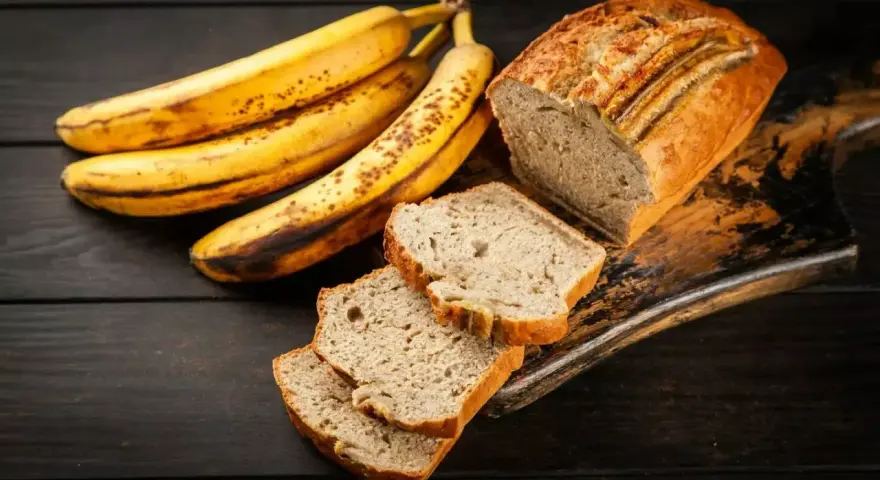 Plátanos maduros junto a un delicioso banana bread recién horneado, con rebanadas listas para disfrutar.