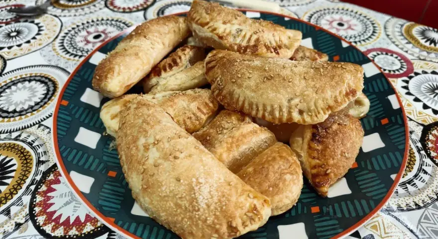 Plato lleno de empanadillas de cabello de ángel, doradas y espolvoreadas con semillas de sésamo.