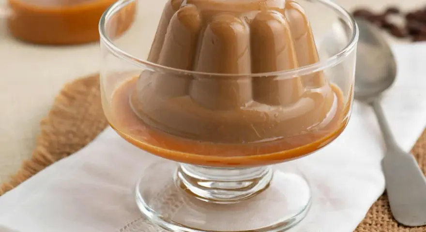 Deliciosa panna cotta de café, con un suave caramelo líquido, servida en copa de cristal.