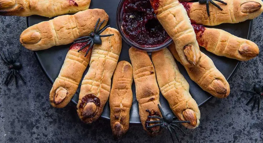 Galletas con forma de dedos, decoradas con almendras como uñas y mermelada roja simulando sangre. Un espeluznante postre de Halloween.
