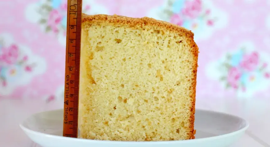 Rebanada de bizcocho de yogurt esponjoso, con una regla de madera al lado para medir su altura.